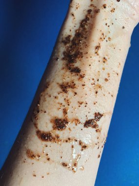 Mavi arka planda kahve fırçası olan genç bir kadın eli. Kozmetik ve kozmetik ürünleri. Güzellik ve cilt bakımı