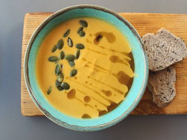 Tahta kesim tahtası ve ekmek parçalarıyla kabak çorbası. Sağlıklı vejetaryen gıda konsepti. Üst görünümü kapat