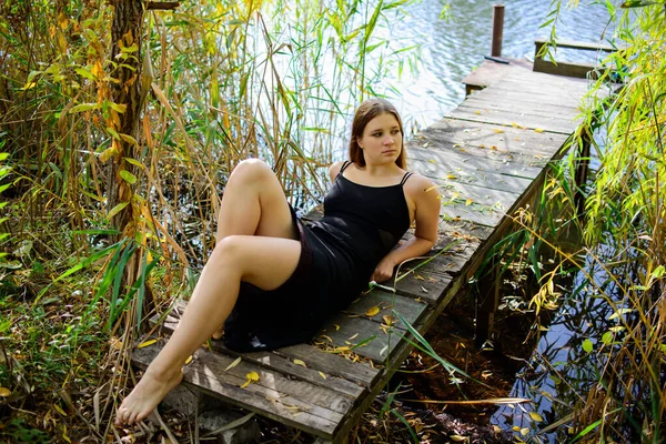 Blond Kvinna Svart Lång Klänning Träpir Vid Flodstranden Vackra Landskap — Stockfoto