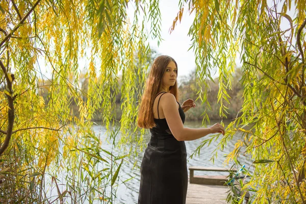 Nehir Kıyısındaki Ahşap Iskelede Siyah Uzun Elbiseli Sarışın Bir Kadın — Stok fotoğraf