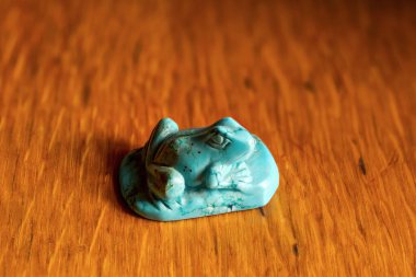 Tahta bir masanın üzerindeki dekoratif taştan yapılmış bir kurbağa heykeli..