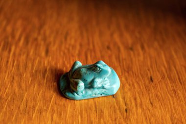 Tahta bir masanın üzerindeki dekoratif taştan yapılmış bir kurbağa heykeli..