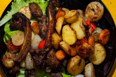 Izgara kuzu kaburgası ve siyah tabakta fırında sebze. Üst manzara, düz uzanma