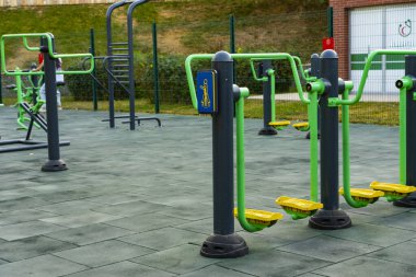 Parlak yeşil ve sarı spor makineleri olan modern açık hava spor salonu halka açık bir parkta, fitness ve sağlıklı yaşam tarzını destekliyor.