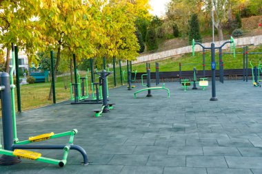 Parlak yeşil ve sarı spor makineleri olan modern açık hava spor salonu halka açık bir parkta, fitness ve sağlıklı yaşam tarzını destekliyor.