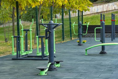 Parlak yeşil ve sarı spor makineleri olan modern açık hava spor salonu halka açık bir parkta, fitness ve sağlıklı yaşam tarzını destekliyor.