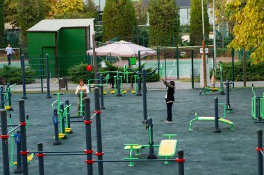 Taşkent, Özbekistan, 9 Ekim 2025: İnsanlar şehir parkında açık spor aletleri kullanıyorlar. Spor aletleri ve yeşil çevresi olan halka açık spor alanı, sağlıklı yaşam tarzını ve açık hava sporlarını destekliyor.
