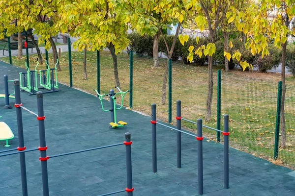 Parlak yeşil ve sarı spor makineleri olan modern açık hava spor salonu halka açık bir parkta, fitness ve sağlıklı yaşam tarzını destekliyor.