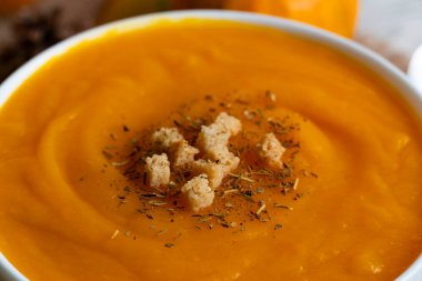 Kıtır kıtır ekmek ve otlarla kaplı ılık bir kase kremalı balkabağı çorbası. Sonbahar tarifleri, konforlu yemek blogları ve mevsimlik mutfak temaları için mükemmel.