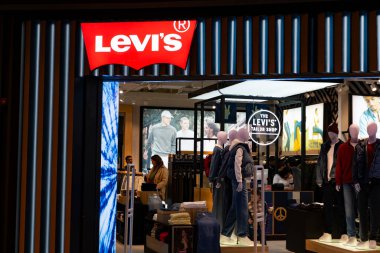 Taşkent, Özbekistan, 02 Şubat 2026: Markalı mankenler, neon terzi tabelası ve modern bir perakende alanında düzgün bir şekilde sergilenen kıyafetler içeren Levis mağazası iç mimarisi