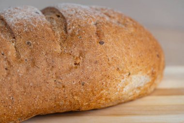 Tahta bir tahtanın üzerinde taze ev yapımı ekmek ve ahşap bir masanın üzerinde buğday kulakları. Doğal fırın konsepti, geleneksel pişirme ve organik gıda