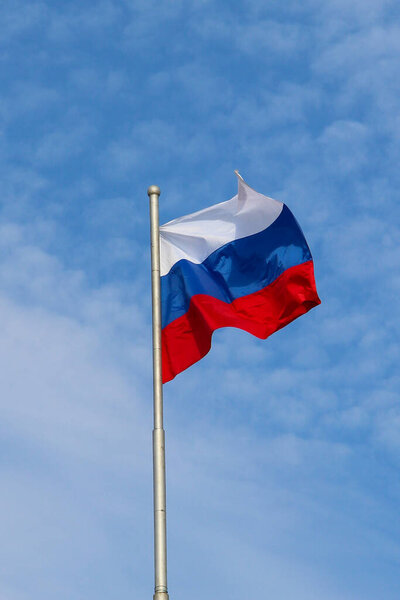 Flag of the Russian Federation streaming in the wind against the blue sky