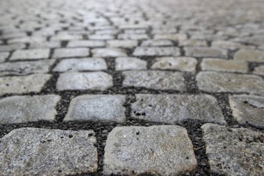 Dikdörtgen granit bloklarla döşenmiş eski bir taş kaldırım blokları ve bloklar arasında ezilmiş kaya cezaları. Seçici odak ile perspektif fotoğraf
