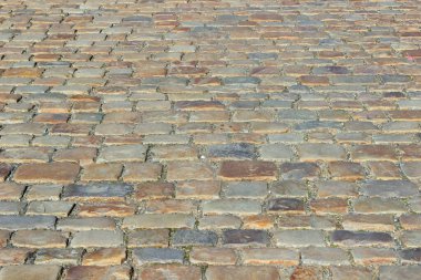 Farklı renklerde dikdörtgen şeklindeki taş bloklarla döşenmiş eski bir taş kaldırım. Seçici odak ile perspektif fotoğraf