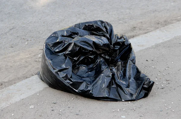 Black garbage bag with trash on the road