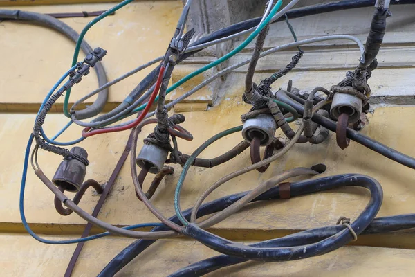 Four old-fashioned out-of-date ceramic insulators for a hand-made electric line mounted on an old dirty yellow wall