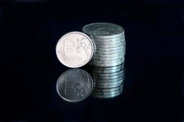 Russian ruble coin and a pile of 2-ruble coins on a black mirroring surface
