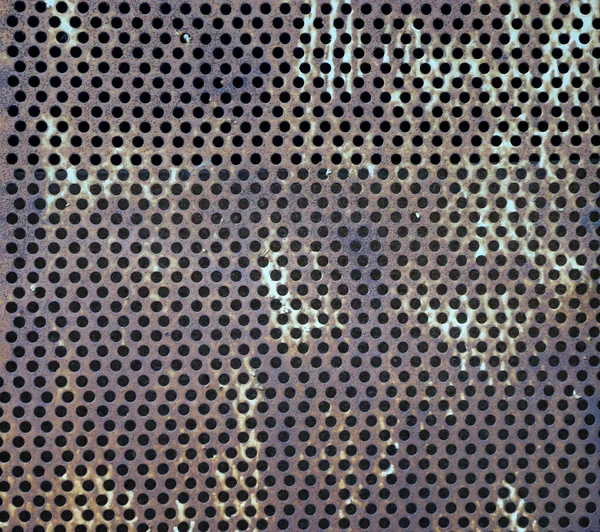 Eski, paslı, yuvarlak bir deliğin dokusu delinmiş metal.