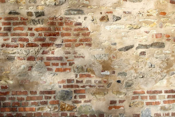 Doğal kaya ve tuğlalardan yapılmış eski duvar kısmen alçıyla kaplanmış.