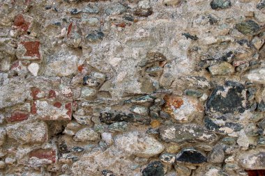 Ağır hasar görmüş beton kalıntılarıyla kaplı eski bir taş duvarın dokusu.