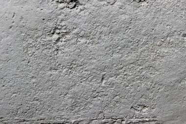 Betondan ve ezilmiş taştan yapılmış ve gri boyayla boyanmış bir duvar dokusu.