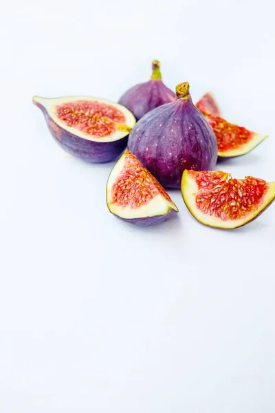 Figos maduros suculentos brilhantes em um fundo branco cortado em pedaços. O conceito de alimentação saudável. — Fotografia de Stock