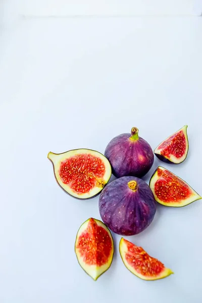 Figos maduros suculentos brilhantes em um fundo branco cortado em pedaços. O conceito de alimentação saudável. — Fotografia de Stock