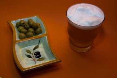 Köpüklü bira ve turuncu arka planda biraz zeytin.