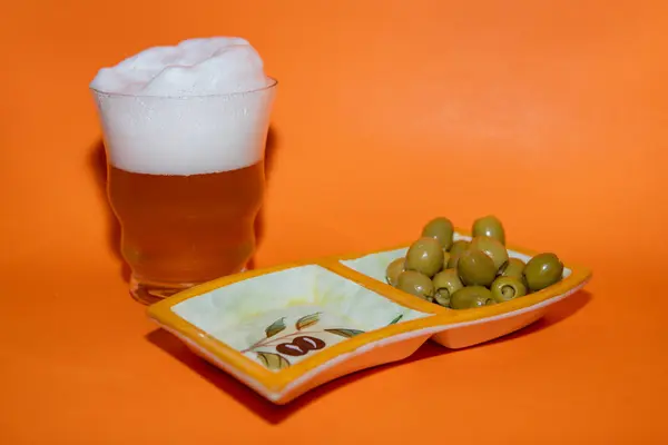 Пиво Большим Количеством Пены Оливок Оранжевом Фоне — стоковое фото