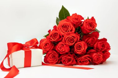 Parlak kırmızı gül buketi, beyaz bir zemin üzerinde parlak bir kurdele ve mesaj yeri olan hediye paketi, tebrik kartı konsepti mutlu Sevgililer Günü, 8 Mart, mutlu yıllar.