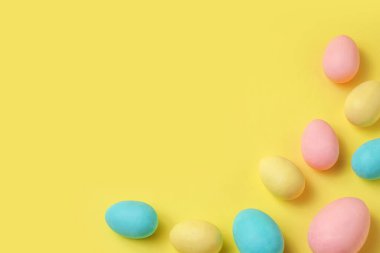Dekoratif kompozisyon - Pastel renklerde paskalya yumurtaları ve sarı bir arka plan. Paskalya kutlaması, tebrik kartı, bayram davetiyesi. Üst manzara, düz uzanma.