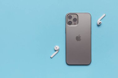 Almaty\ Kazakistan, Şubat 2021 iPhone ve mavi arka planda aktif bir yaşam tarzı için kablosuz kulaklıklar. 