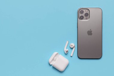 Almaty\ Kazakistan, Şubat 2021 iPhone ve mavi arka planda aktif bir yaşam tarzı için kablosuz kulaklıklar. 