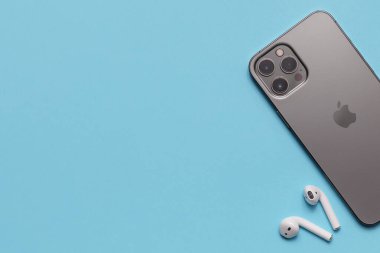 Almaty\ Kazakistan, Şubat 2021 iPhone ve mavi arka planda aktif bir yaşam tarzı için kablosuz kulaklıklar. 