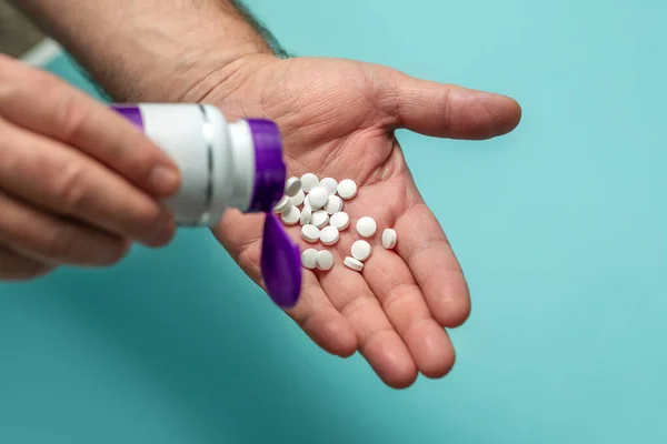 Pharmacy and medical concept, bottle and white round pills in the hands of a man on a blue background. Pharmacy and medical concept