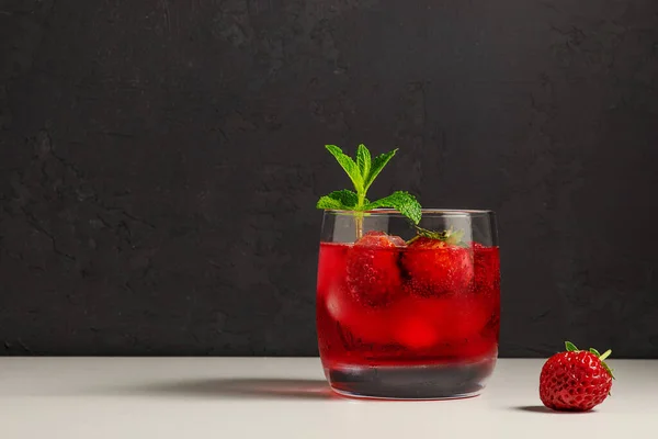cold, homemade, strawberry lemonade with ice in glass glasses, mint leaves and berries on a dark background