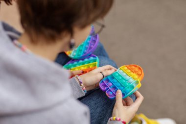 Popit 'le oynayan genç kızlar. Gençlerin elinde yeni bir anti-stres oyuncağı. Akıl sağlığı kavramı. Oyuncak stres ve endişelerle savaşmak için tasarlandı. Modern moda bir oyuncak.