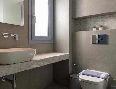 Çağdaş tarzda modern banyo içi pencereli gri çakıl taşı, damar lavabosu, gizli duvar asılı tuvalet.