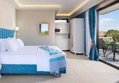 Yaz tatili konsepti için klasik tarz şık bir tatil evinin beyaz ve mavi iç mekanı. Yatak odasındaki pencere terası kırsal manzarası çok güzel.