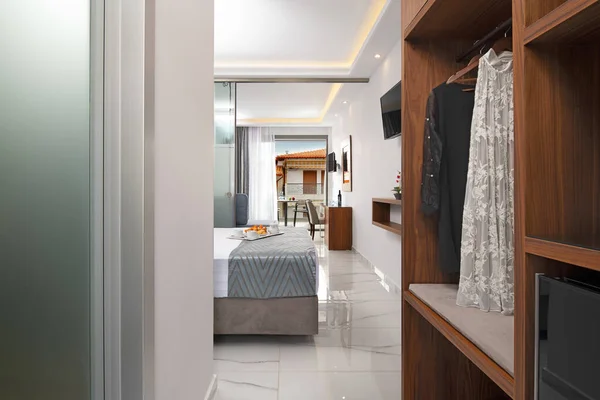 Front view of apartment entrance hallway with wooden wardrobe cabinet. Modern bedroom hotel interior room with open window to old European city street with vintage roof tile house