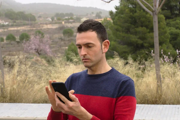 Akıllı telefon kullanan genç bir erkek endişeli bir şekilde ekranı izliyor. Kavram: Evden işe gidiş