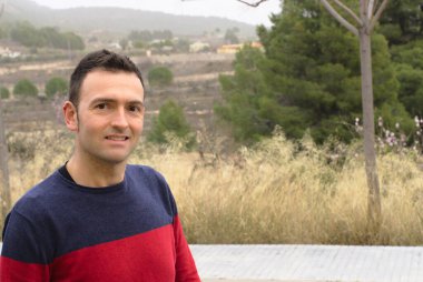 Genç adam sokakta yalnız poz veriyor.