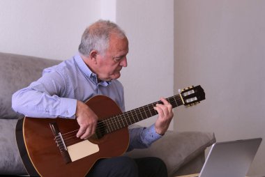 Hapsedilme zamanı müzik kavramı, covid19. Evde tek başına gitar çalan olgun bir adam..