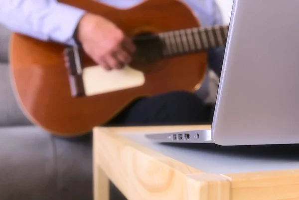 Bilgisayarı kapat. Arka planda, bilgisayar başında oturan gitar akorları çalan olgun bir adamın elleri var. Coronavirus hapsi süresince evdeki müziği kavrayın.