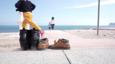 Nisan 2021, Altea, İspanya - Ayakkabılar yakın odaklı. Yalınayak anne ve çocuk arka planda ve kız haçlar