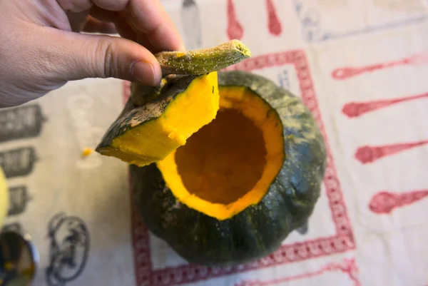 Hands of unrecognizable caucasian adult woman opening lid of an orange and green jack-o-lantern