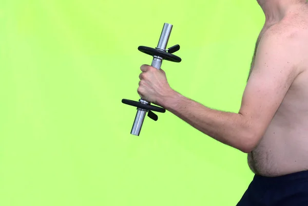 Arm of a middle-aged fat man in his 30s lifting a dumbbell weight to get fit. Concept healthy lifestyle