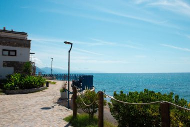 Turkuaz suları ve berrak mavi gökyüzü olan canlı bir kıyı şeridini gösteren resim gibi bir manzara. Sapri, Campania, İtalya.