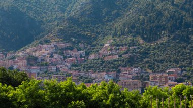 Bir kasaba yeşil ağaçlar ve dağlarla çevrili bir yamaçta oturur. Evler açık gökyüzü ile birlikte birbirine yakın istiflenmiştir. Gündüz oldu ve manzara aydınlık..