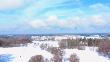 Şehirde soğuk bir günde insanlar kış güneşinde yürürken ve oynarken kar parkı kaplar.